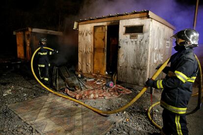 Los bomberos extinguen el fuego de uno de los refugios. El incendio ha destruído muchas de las casas, construidas en madera.