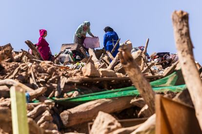 Several women from the village recover their belongings by climbing the mountain of rubble that their house has been reduced to.