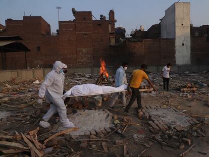 Voluntarios y familiares trasladan el cadáver de una víctima de la covid-19 para su cremación en Nueva Delhi, el pasado día 11.