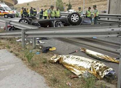 Los cadáveres de los dos adultos fallecidos yacen en el arcén junto al vehículo volcado.