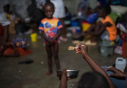 Una madre ofrece a su pequeña hija una cucharada de arroz en refugio improvisado para personas desplazadas por la violencia en Puerto Príncipe, Haití, el 8 de mayo de 2024. 