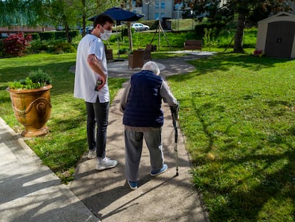 Un trabajador de una residencia en Thises, en el este de Francia, acompaña a una anciana en su paseo por el jardín del centro