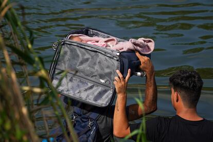 Migrantes cruzan el río Grande con un bebé en el interior de una maleta, cerca de Matamoros (México).