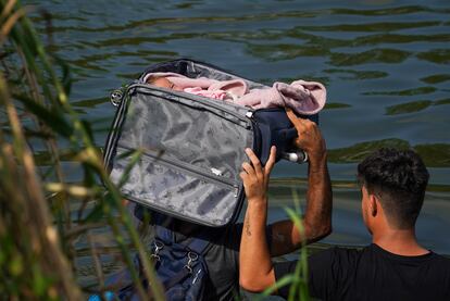 Migrantes cruzan el río Grande con un bebé en el interior de una maleta, cerca de Matamoros (México). 