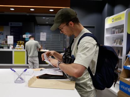Un hombre cumplimenta la documentación para ejercer el voto por correo en una oficina de Madrid.