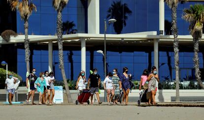 Varias personas caminan a la orilla de la playa en Valencia.