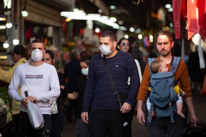 Un grupo de vecinos de Tel Aviv, algunos con mascarillas como protección contra la Covid-19, pasean por las calles de la ciudad israelí.