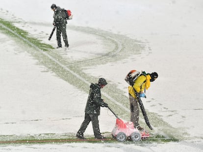 Empleados del Atalanta limpian las rayas del campo y las pintan de rojo para jugar con nieve.