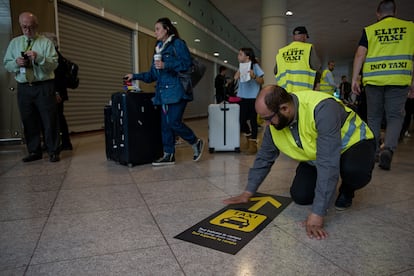 Un taxista coloca en el suelo una pancarta durante la protesta en la T1 del aeropuerto de Barcelona, este lunes.
