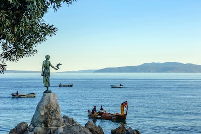 Un barco de pescadores frente a la escultura de 'La niña de la gaviota', en Opatija. 
