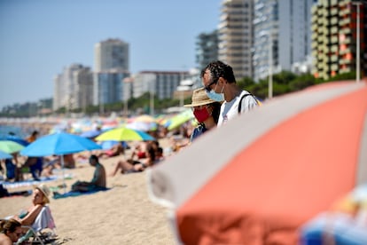 Un matrimonio accede en la playa con mascarillas en Platja d'Aro, este verano.