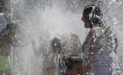 Ni&ntilde;os y mayores se refrescan en Madrid. 