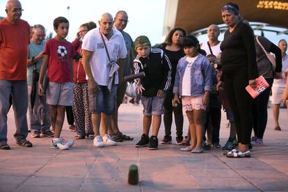 Un hombre enseña a varios niños a jugar a la calva en el parque de Aluche.