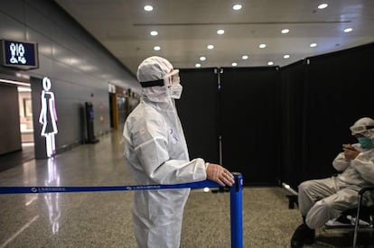 Un agente de seguridad vestido con equipo de protección custodia un acceso en el aeropuerto internacional de Shanghái Pudong.
