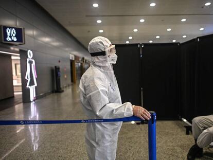 Un agente de seguridad vestido con equipo de protección custodia un acceso en el aeropuerto internacional de Shanghái Pudong.