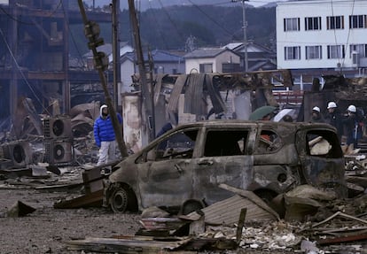 Varias personas contemplan los daños causados en una zona residencial incendiada tras el terremoto en Wajima, este martes.