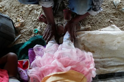 Satyendra Kuma, un trabajador migrante, masajea los pies de su hija tras caminar durante tres días, antes de cruzar la frontera hacia su Estado natal, Uttar Pradesh.