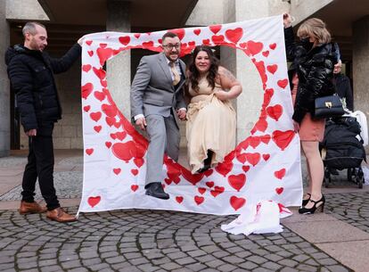 Una pareja de recién casados atraviesa una tela decorada con corazones después de su ceremonia nupcial en el ayuntamiento de la ciudad alemana de Colonia.