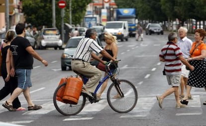 Un hombre transporta dos bombonas en una bici.