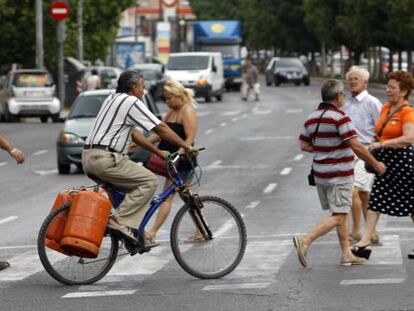 Un hombre transporta dos bombonas en una bici.
