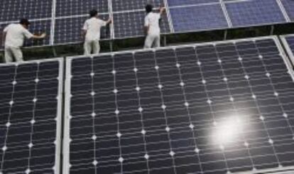 Trabajadores colocan paneles solares en Baoding (China).