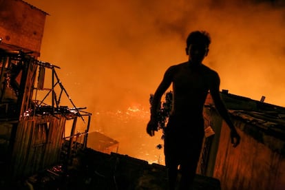 Un residente ayuda durante las labores de los bomberos en un incendio masivo en el vecindario de Educandos, en Manaus (Brasil). Según el Departamento de Defensa Civil de Manaus, el incendio destruyó al menos 600 casas y su origen aún se desconoce. 