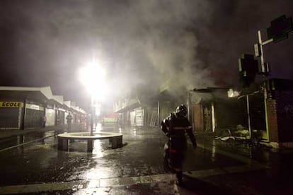 Un bombero abandona una zona comercial de la ciudad de Evreux, al oeste de Francia, aún humeante tras haber sido incendiada.