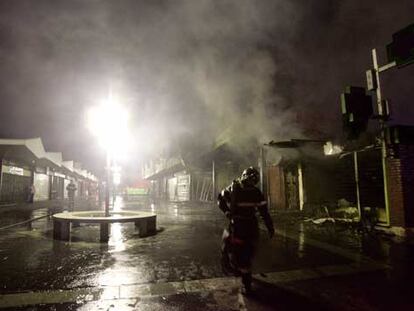 Un bombero abandona una zona comercial de la ciudad de Evreux, al oeste de Francia, aún humeante tras haber sido incendiada.