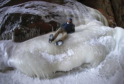 El hombre se desliza por la pared de hielo cerca de las cuevas de las Islas Apostle.
