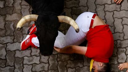 Un toro de la ganadería Fuerte Ymbro pasa por encima de un mozo, durante el cuarto encierro de los Sanfermines 2024 este miércoles, en Pamplona.