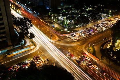 Rastros de la luz de la larga exposición del tráfico en un cruce en el distrito de Makati de Manila (Filipinas).