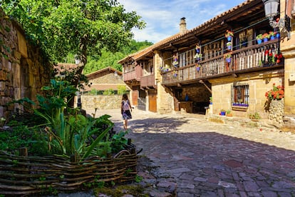 Casas tradicionales con balconadas de madera adornadas con plantas en una calle de Bárcena Mayor (Cantabria).