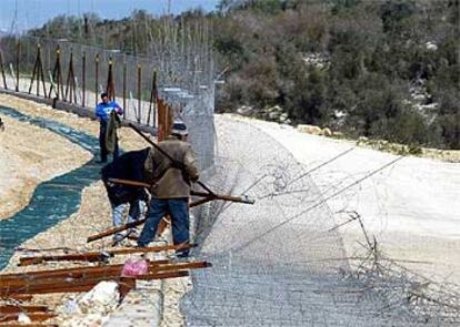 Varios trabajadores desmantelan una pequeña parte del muro levantado por Israel.