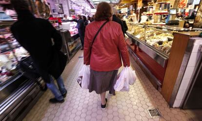 Una mujer acarrea con varias bolsas en el Mercado Central de Valencia