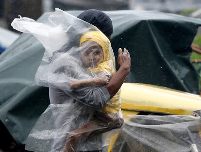 Un residente protege a su hijo del fuerte viento y lluvia con un plástico por el paso del tifón Rammasun en el barrio de chabolas de Tondo, en Manila (Filipinas).
