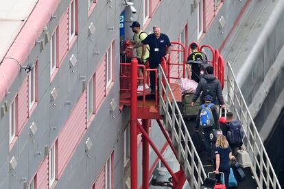 Varias personas con equipaje suben al buque 'Bibby Stockholm', reconvertido en centro de migrantes, en el puerto de Portland, este lunes.