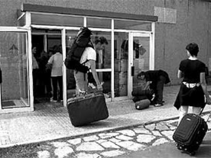 Pasajeros con destino a Barcelona recogen sus maletas perdidas en el aeropuerto de El Prat.
