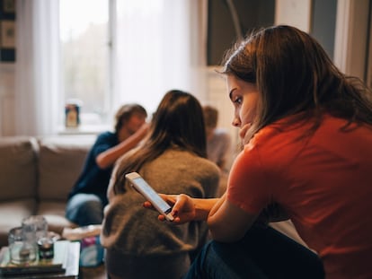 Girl using smart phone while sitting with friends in living room