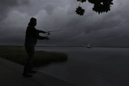 Un hombre pesca ante la inminente llegada del huracán Dorian, mientras un barco camaronero toma puerto seguro en St. Mary's, Georgia.