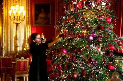 Personal de la Royal Collection Trust decorando el árbol navideño en el que, este año, destacan entre los tradicionales adornos rojos y dorados, varios en color púrpura, el preferido de Isabel II.