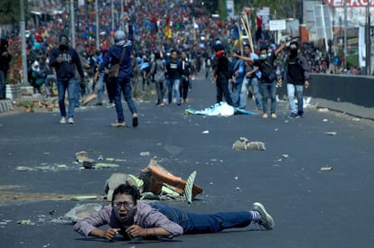 Un hombre yace en el suelo de la carretera en la que se está llevando a cabo una protesta de estudiantes universitarios en Makassar (Indonesia).