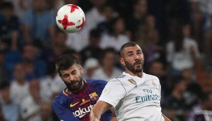 Piqu&eacute; disputa un bal&oacute;n con Bemzema. 