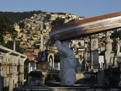 Dos personas cargan el ataúd de una persona fallecida por coronavirus en un cementerio de Rio de Janeiro, Brasil.