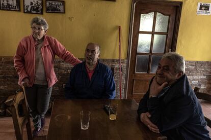 Amador Verdasco (centro) y Elvira Verdasco (izquierda) charlan con un cliente de su bar, que se salvó de las llamas por escasos metros, situado en el confín de los concejos de Valdés y Tineo, Asturias.