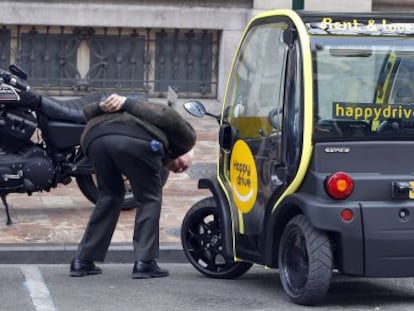 Un hombre observa un coche eléctrico en el Ayuntamiento de Valencia.