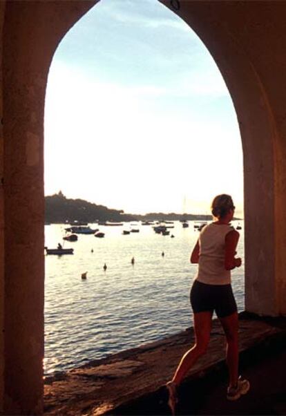 Una mujer corre al borde del mar en Cadaqués (Girona).