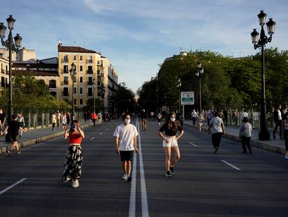 Varias personas caminan el pasado domingo por la calzada para mantener la distancia en el viaducto de Segovia, en Madrid.