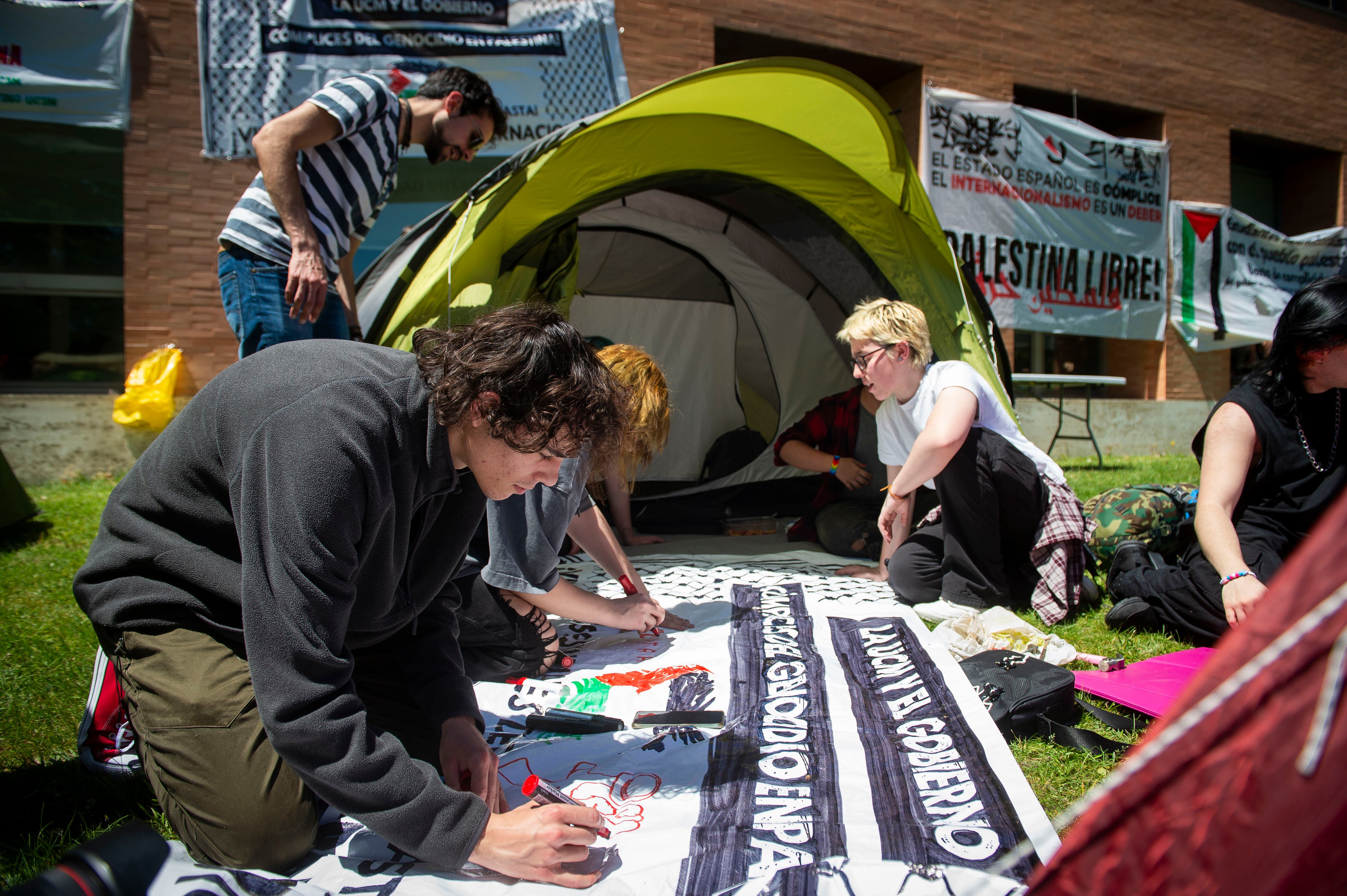 Estudiantes madrileños acampados en la Universidad Complutense pintan una pancarta en favor de Palestina.