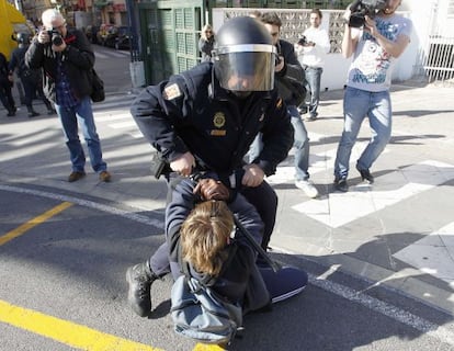 Un polic&iacute;a retiene a un joven estudiante contra el asfalto en el centro de Valencia.