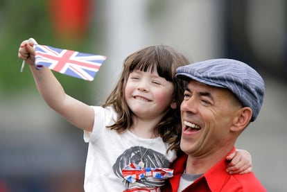 Una niña ondea una bandera al paso de la carroza real.